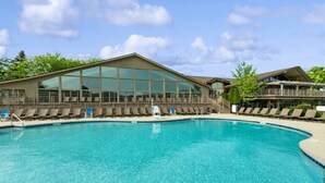 A swimming pool with lounge chairs and a building with large windows. - Deerpath Retreat at Abbey Springs (Fontana-on-Geneva Lake)