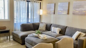 A modern living room with a sectional sofa, a coffee table, and a dining area with chairs. - Deerpath Retreat at Abbey Springs (Fontana-on-Geneva Lake)