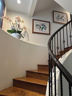 A wooden staircase with a black balustrade, white walls, and two framed artworks. - Beautiful 3-bedroom house with AC in peaceful Manhattan Beach Sand Section (Manhattan Beach)