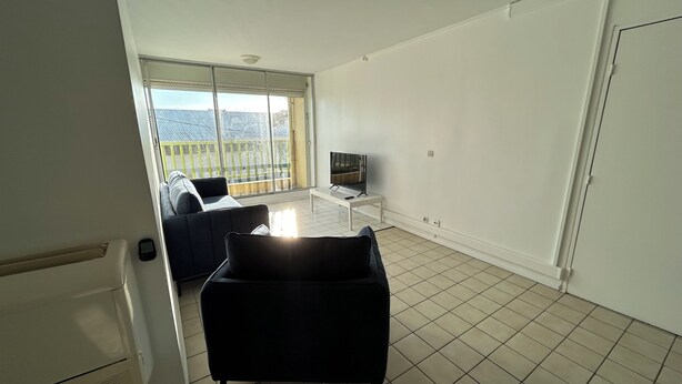 A spacious living room with a large window, a flat-screen TV, and a black sofa. - 🏖️ Spacious 3-bedroom air-conditioned apartment with sea view in Pointe-à-Pitre (Pointe-à-Pitre)