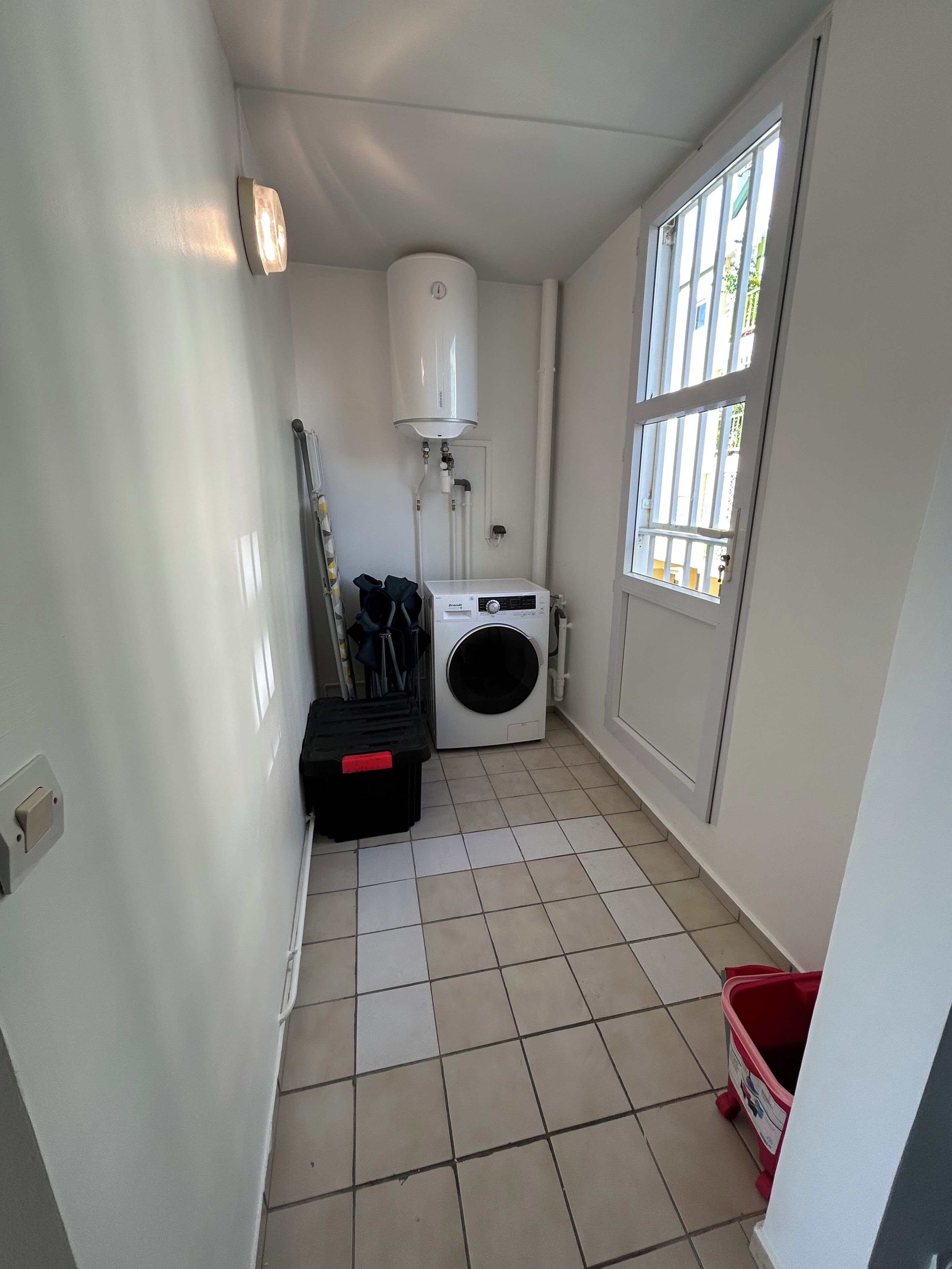 Une buanderie équipée d’un lave-linge, d’un sèche-linge, d’un chauffe-eau et d’une fenêtre.