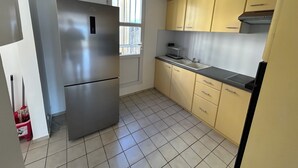 A kitchen with a stainless steel refrigerator, a sink, and yellow cabinets. - 🏖️ Spacious 3-bedroom air-conditioned apartment with sea view in Pointe-à-Pitre (Pointe-à-Pitre)