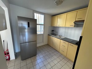 Eine Küche mit einem Edelstahl-Kühlschrank, einer Spüle und gelben Schränken.