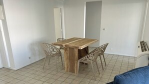 A dining area with a wooden table and four chairs, a tiled floor, and a blue couch in the foreground. - 🏖️ Spacious 3-bedroom air-conditioned apartment with sea view in Pointe-à-Pitre (Pointe-à-Pitre)