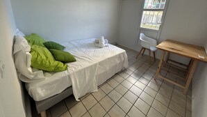 A small, clean room with a bed, a desk, and a window. - 🏖️ Spacious 3-bedroom air-conditioned apartment with sea view in Pointe-à-Pitre (Pointe-à-Pitre)