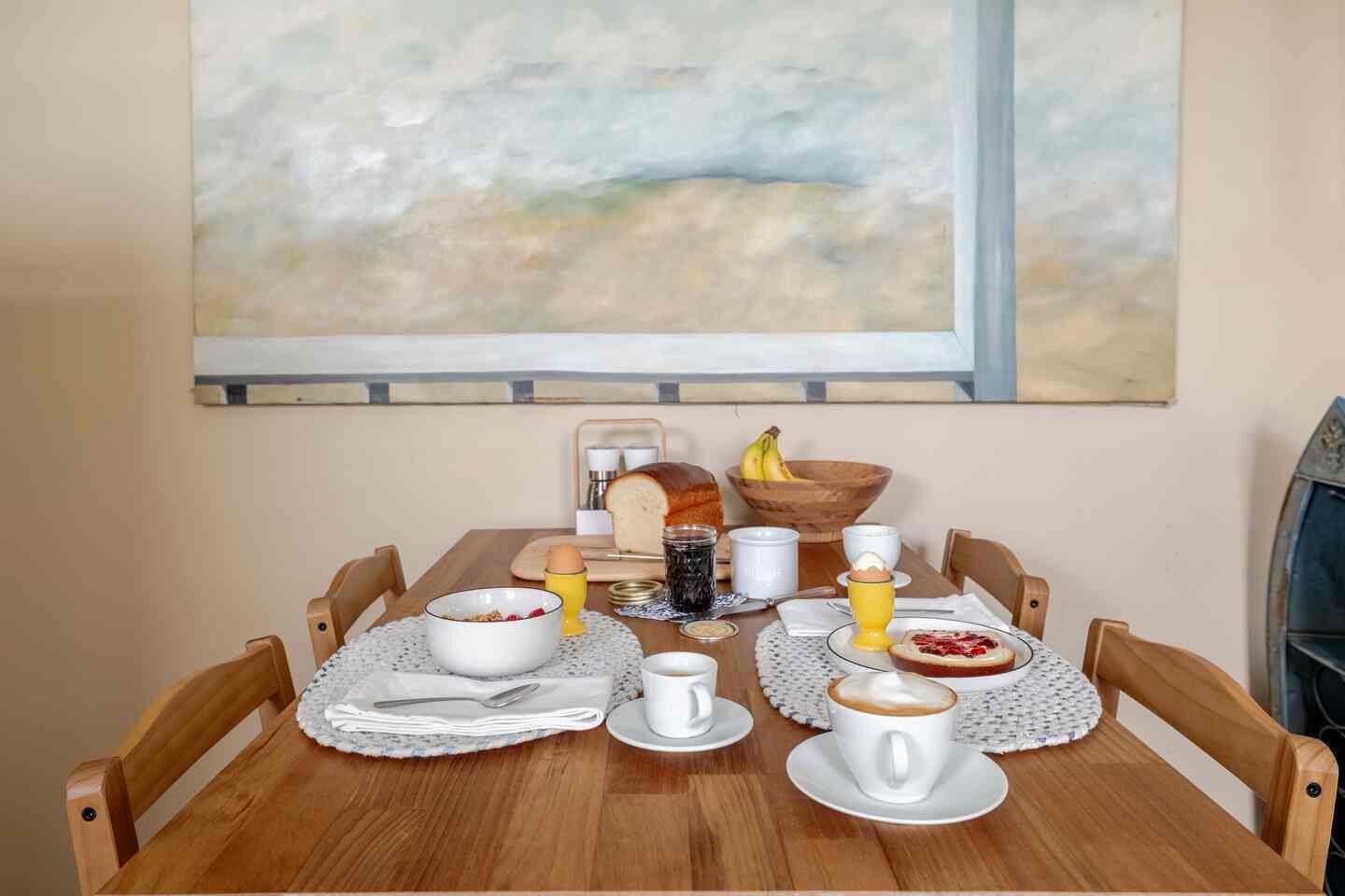 Un desayuno con una mesa, sillas, un cuadro y una ventana.