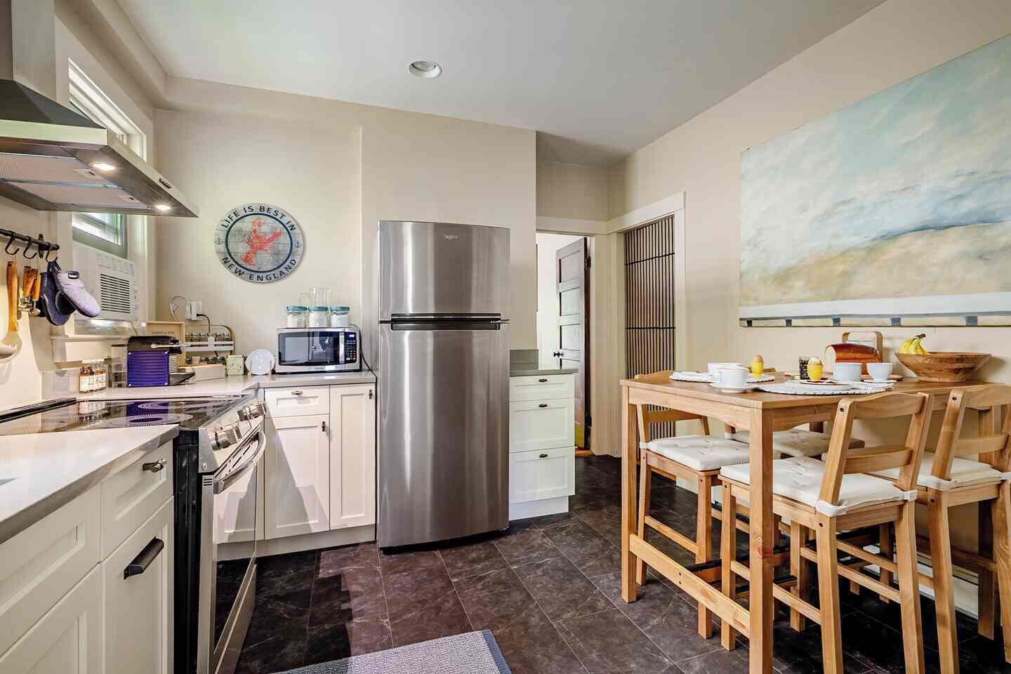 Una cucina moderna con elettrodomestici in acciaio inossidabile, una zona pranzo con mobili in legno e vista sul mare.