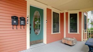 A house with a green door, a porch with a bench, and mailboxes on the side. - Classic charm with modern comforts near Harvard. (Cambridge)