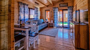 A wooden cabin interior with a dining area, sofa, and television. - Holiday Homes With Terraces, Sauna + Whirlpool (gmina Będzino)