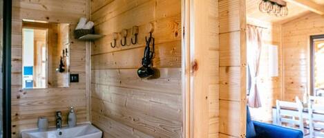 A wooden cabin interior with a wooden wall, a white sink, and a blue sofa.