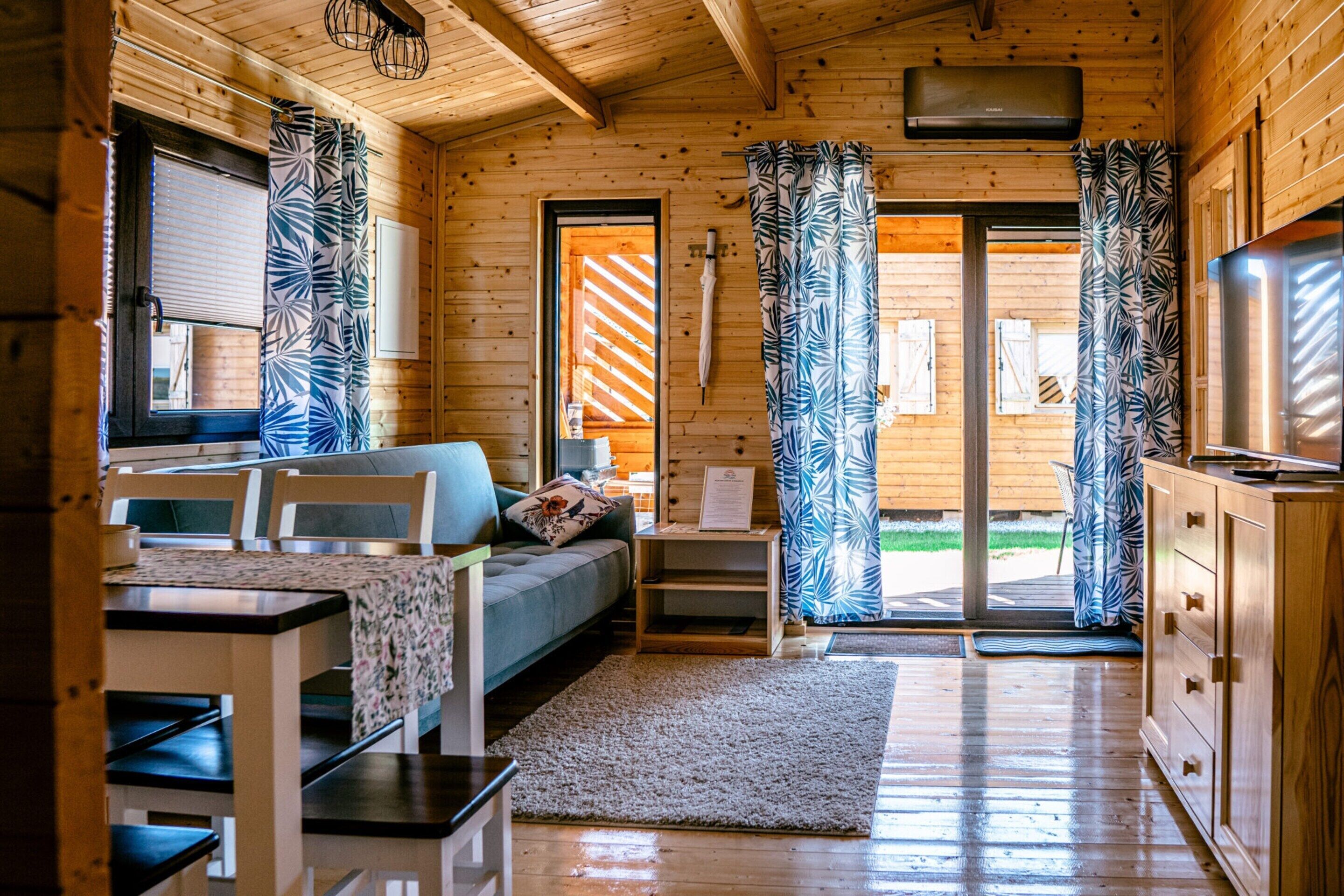A cozy cabin interior with a bed, a desk, and a TV.