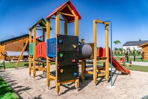 Ein Spielplatz mit Kletterwand, Rutschen und Schaukeln.