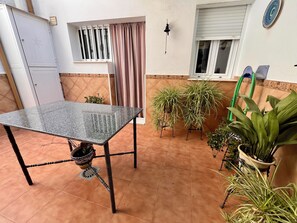A patio with a table, potted plants, and a window with blinds. - Casa Vista Hermosa next to Natural Park - Sleeps 8 - Centro Andalucía (Rute)