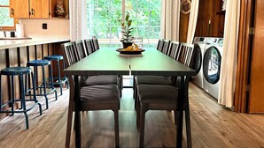 A dining area with a long table, chairs, and a potted plant. - Smoky Mountain Creekside Retreat - Private Cabin with Backyard Stream (Maggie Valley)