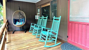 A porch with wooden flooring, a hanging chair with cushions, and two rocking chairs. - Smoky Mountain Creekside Retreat - Private Cabin with Backyard Stream (Maggie Valley)