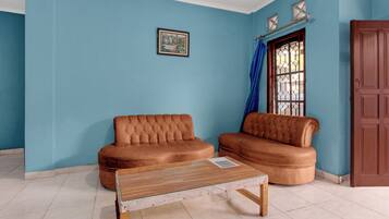 A room with two brown sofas, a wooden coffee table, a window with blue curtains, and a door.
