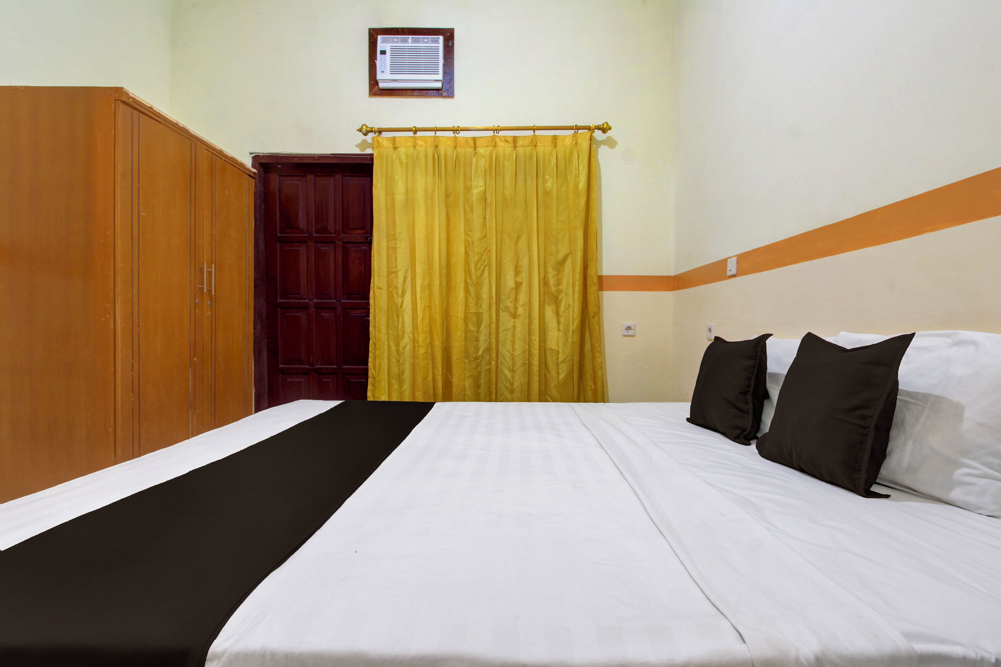 Una habitación de hotel con cama, armario y cortina.