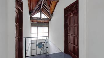 A hallway with a wooden ceiling, a glass door, and a metal gate.