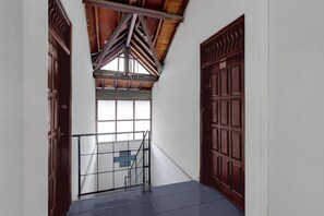 A hallway with a wooden ceiling, a glass door, and a metal gate. - Hotel O Lowanu Stay Syariah (Yogyakarta)