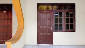 A building with a brown door and a window with multiple panes. - Hotel O Lowanu Stay Syariah (Yogyakarta)