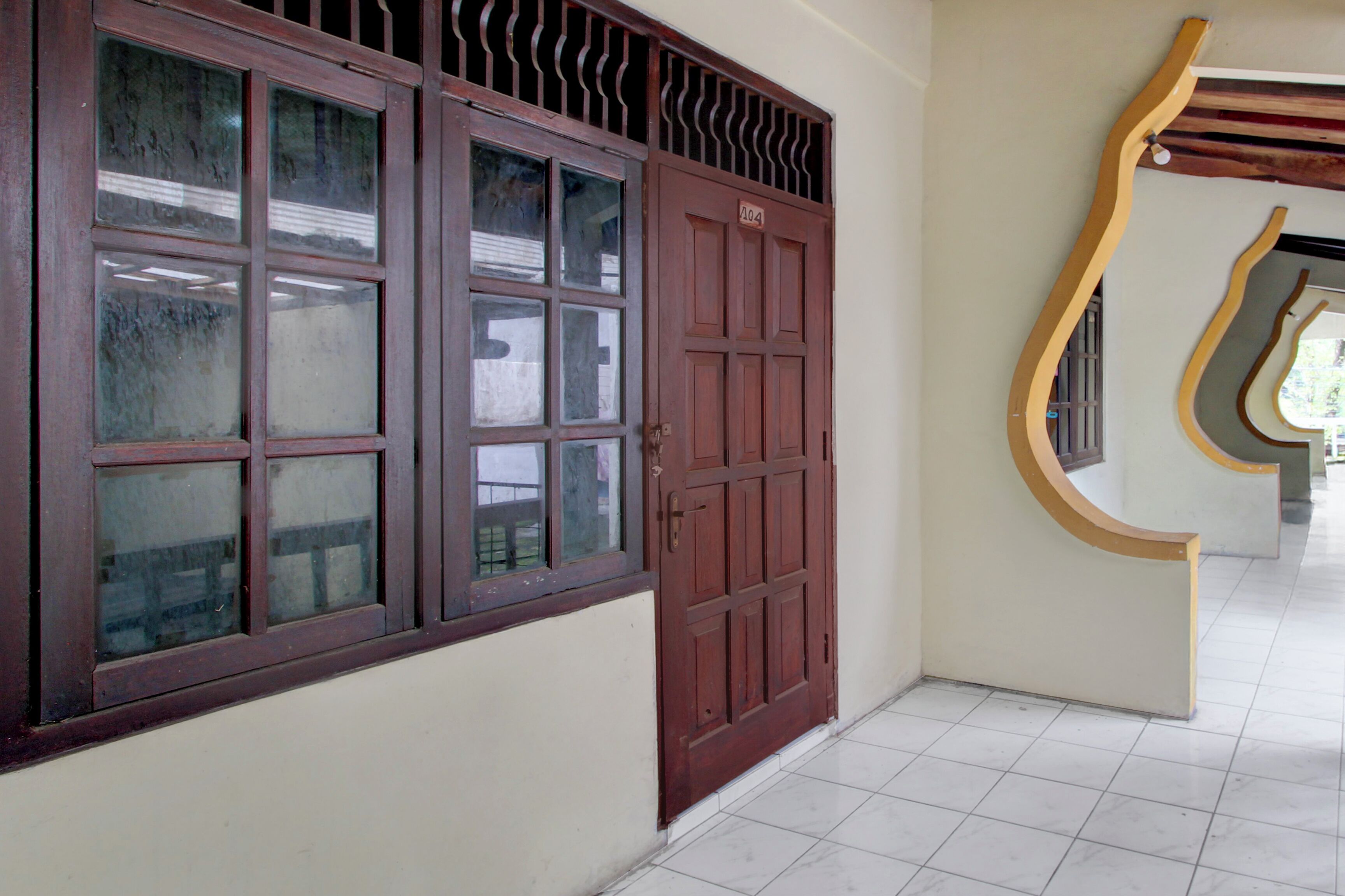 Un pasillo con una puerta de madera grande y una ventana con reja de metal.