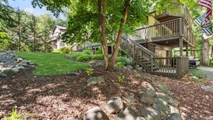 A residential area with a wooden deck, a stone pathway, and a well-maintained lawn. - Treetop Lakehouse at Abbey Springs (Fontana-on-Geneva Lake)