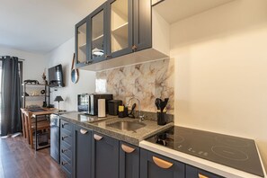 A modern kitchen with dark cabinetry, a marble backsplash, and a built-in stove. - Studio 406 Perdizes 900m Allianz Parque c Academia (São Paulo)