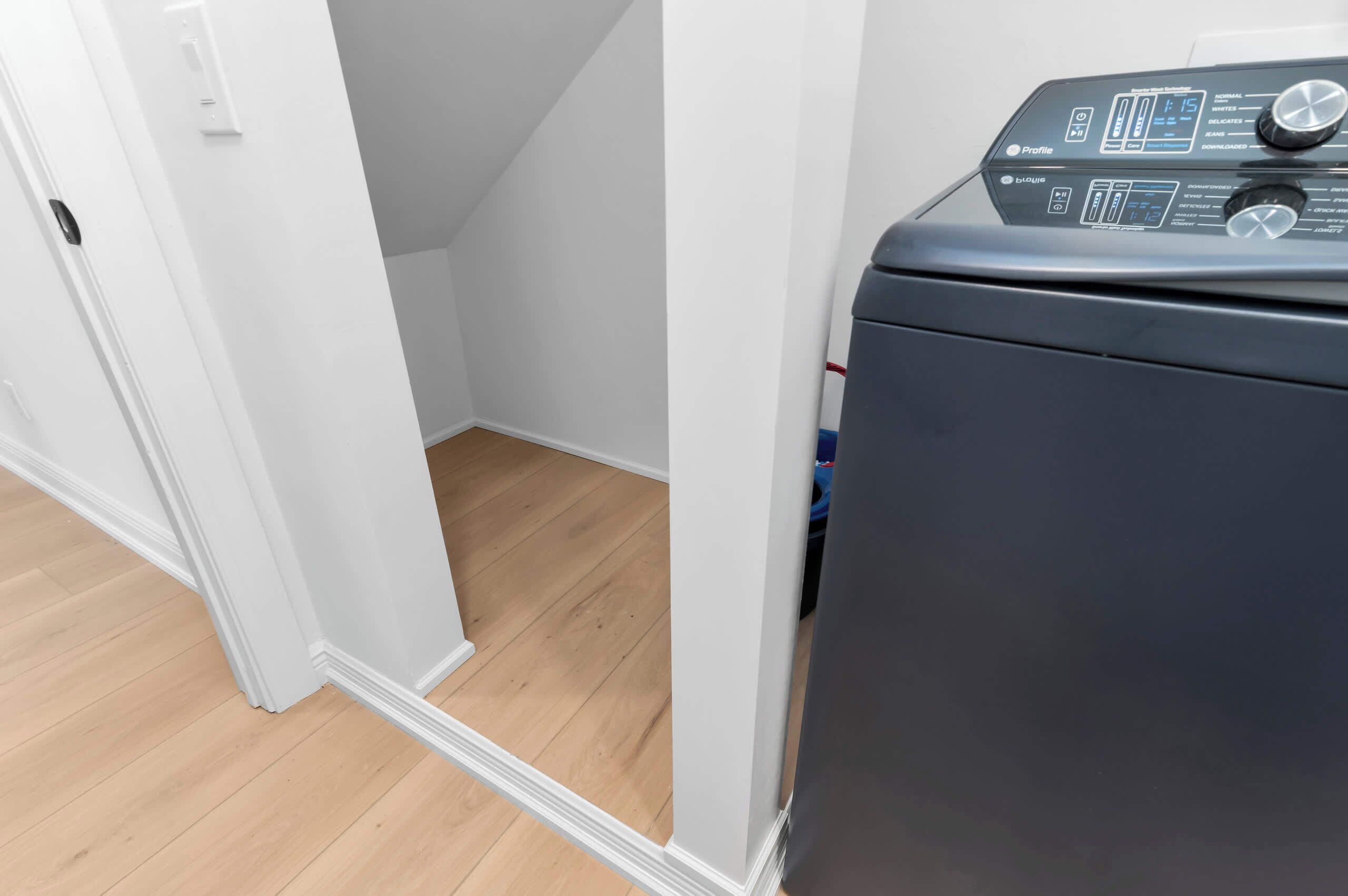 A laundry machine in a room with white walls and wooden flooring.