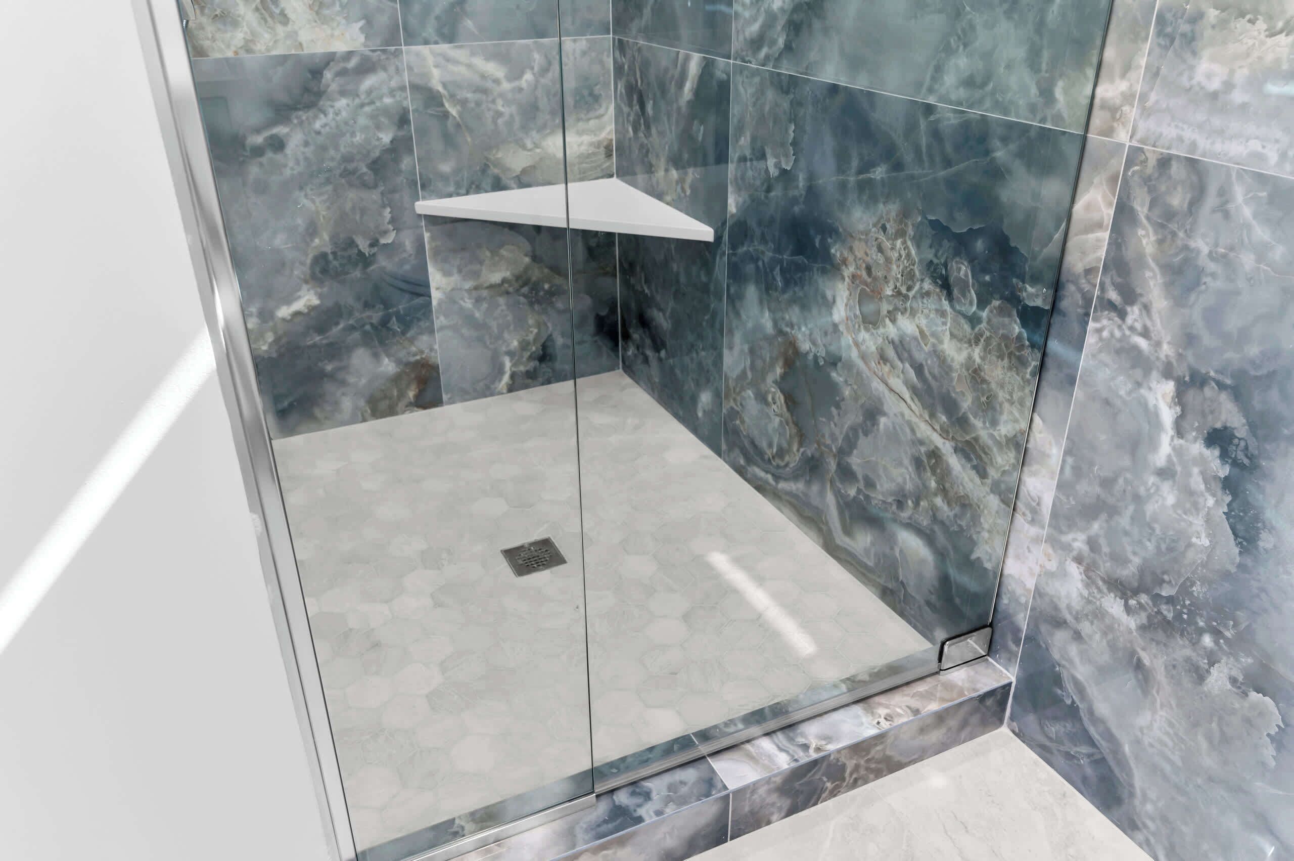 Un espace douche moderne doté d’une paroi en verre et d’un mur en marbre.