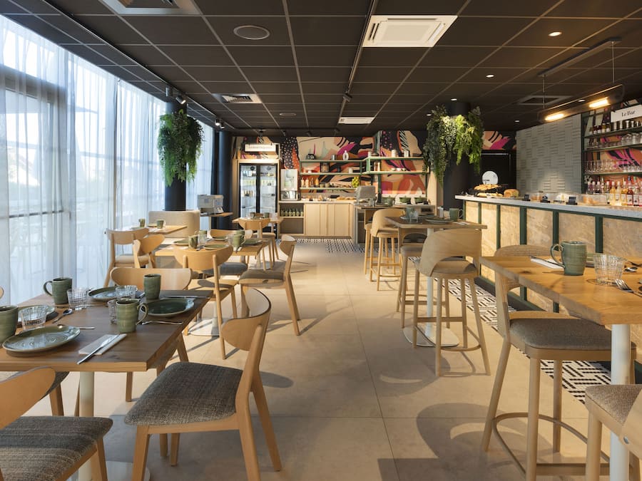 A cafe with multiple seating areas, including tables and chairs, and a bar counter with various items.