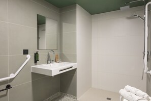 Une salle de bain moderne avec un lavabo blanc, une douchette à main et un porte-serviettes avec des serviettes.