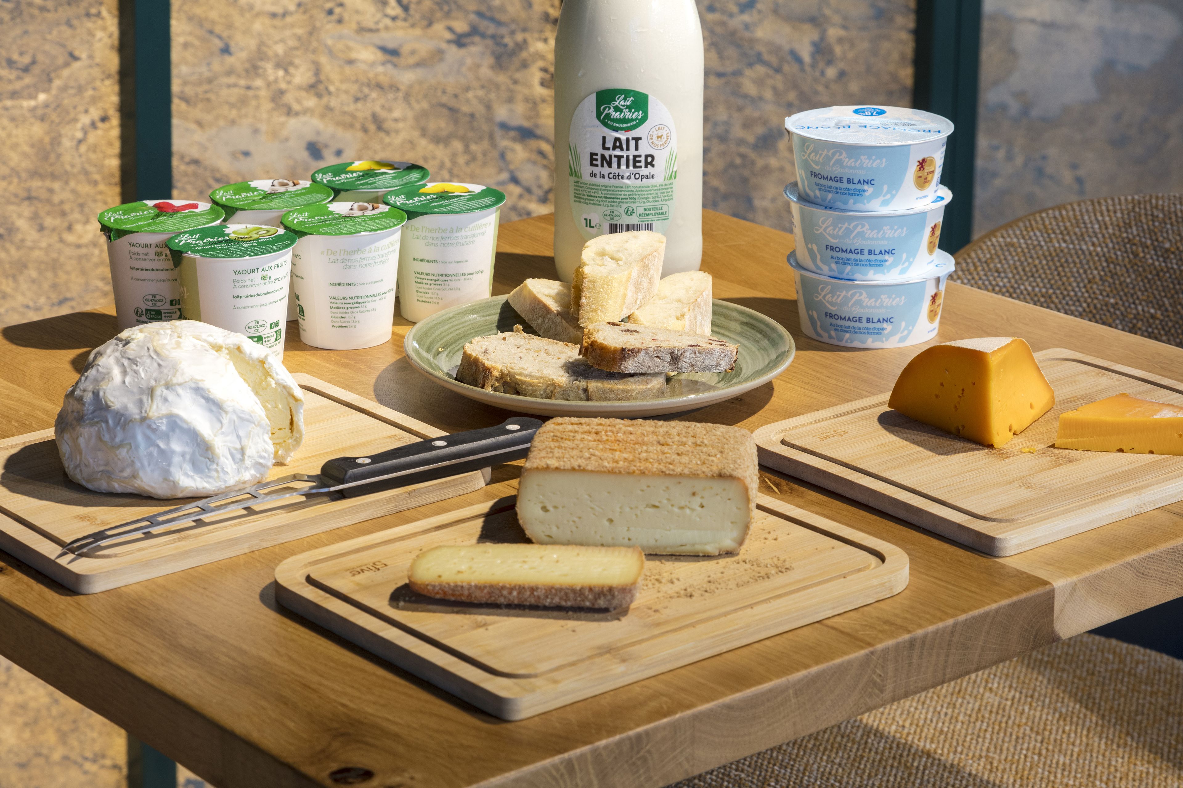 Une variété de fromages et de produits laitiers disposés sur une table en bois.