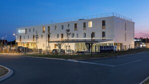 Un edificio moderno di un hotel con tetto piatto, numerose finestre e un'area d'ingresso coperta.
