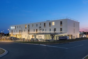 Un hotel moderno con techo plano, múltiples ventanales y un área de entrada cubierta.