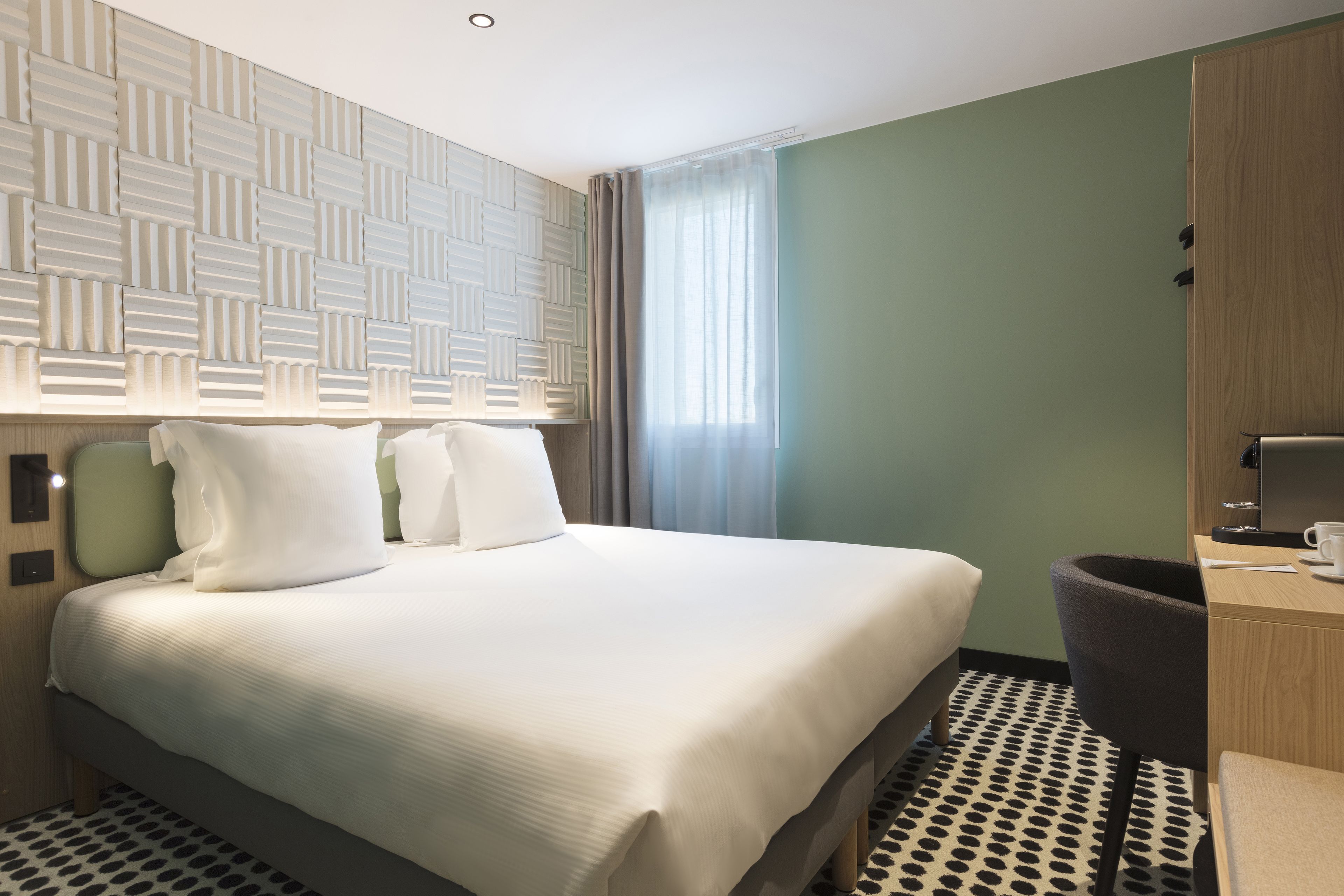 Una habitación de hotel con una cama grande, un escritorio con silla, un armario y piso estampado.