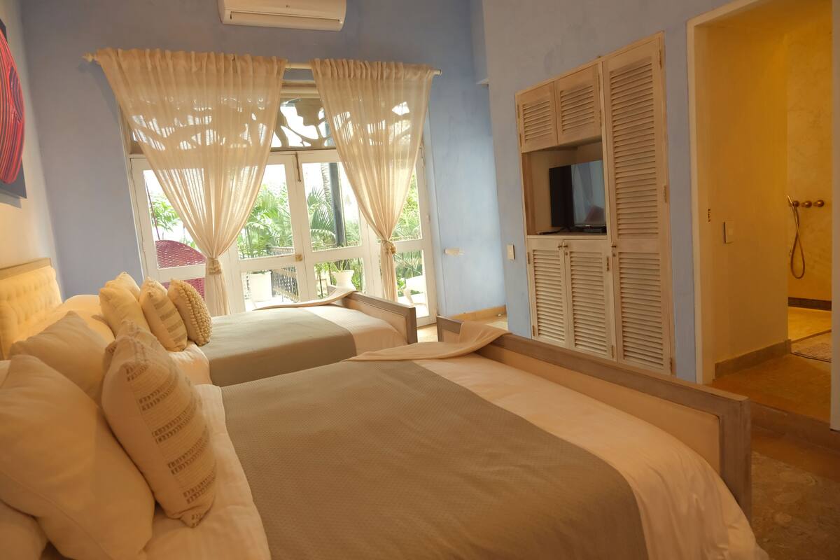 Une chambre avec deux lits, une télévision et un espace douche.