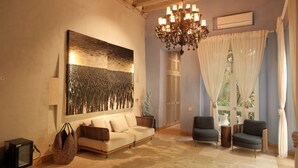 A cozy living room with a large abstract painting, a chandelier, and a sofa. - Hotel Casa Santiago Botero (Cartagena)