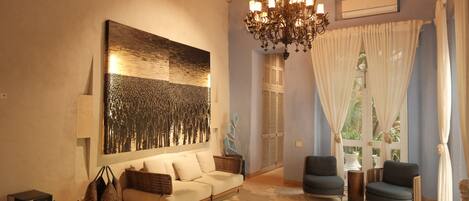Ein gemütliches Wohnzimmer mit einem großen abstrakten Gemälde, einer Chandelüster und einem Sofa.