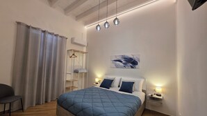 A bedroom with a bed, bedside tables, a hanging light fixture, a coat rack, and a window with curtains. - Marèa - Holiday House (Porticello)