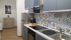 A modern kitchen with grey cabinets, a stainless steel sink, and a tiled backsplash with floral patterns. - Marèa - Holiday House (Porticello)