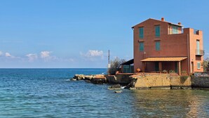 A coastal building with a stone foundation, a flat roof, and a balcony. - Marèa - Holiday House (Porticello)