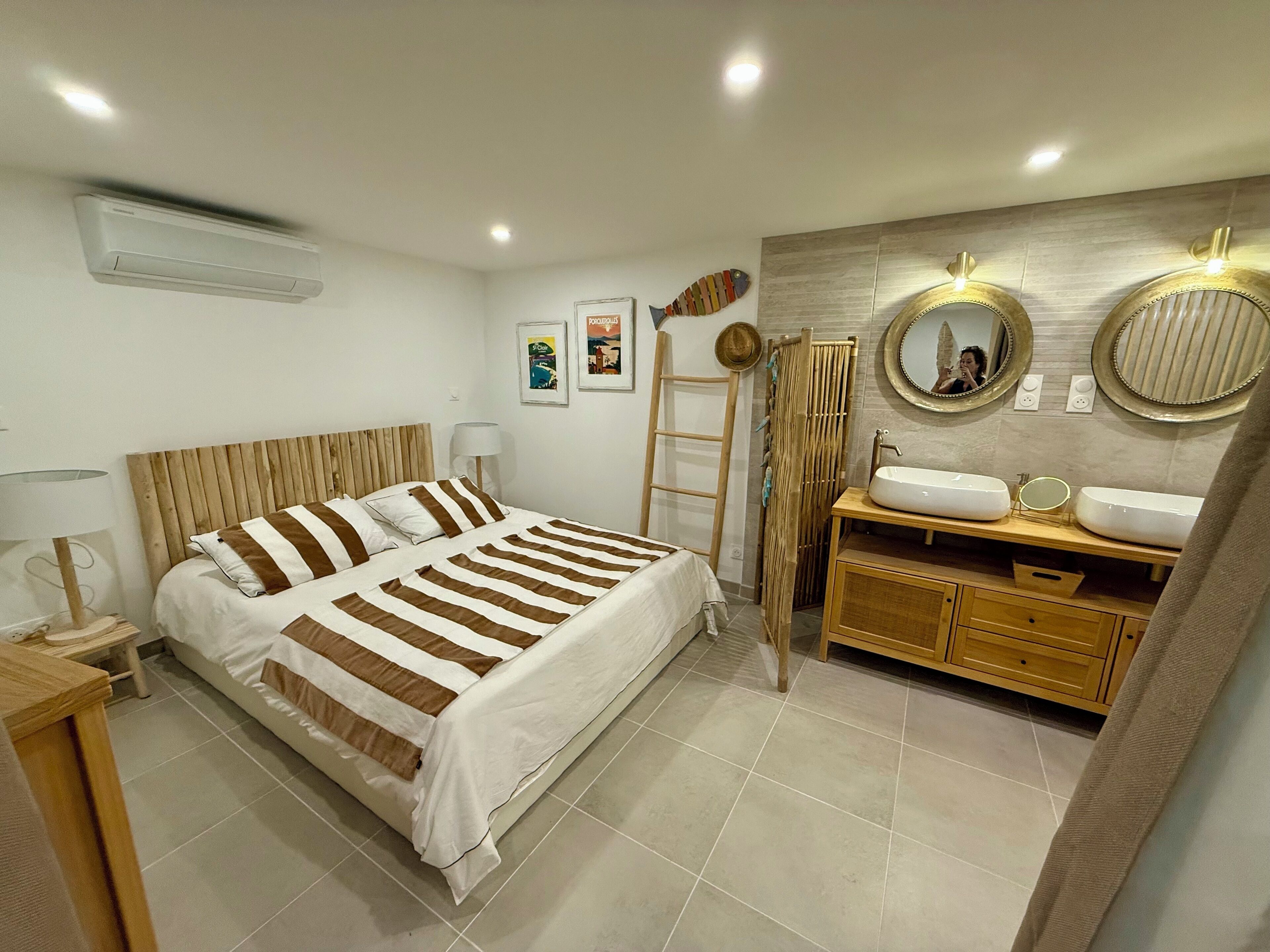 A bedroom with a bed, bedside tables, a vanity with a mirror, and a towel rack.