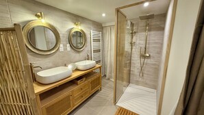 Ein modernes Badezimmer mit zwei Waschbecken, einer Glasdusche und Holzschränken.