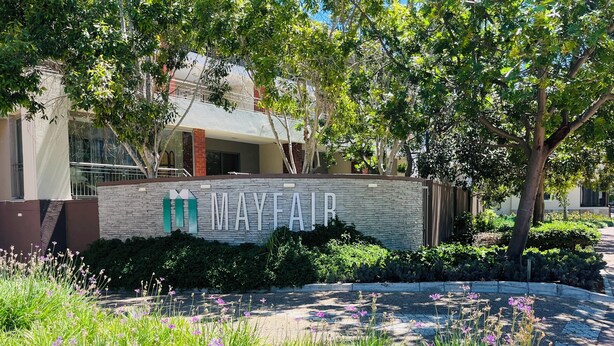 A stone wall with the name 'MAYFAIR' and a landscaped garden with purple flowers. - WELCOME TO 144 @ MAYFAIR — YOUR URBAN OASIS IN CENTURY CITY, CAPE TOWN! (Cape Town)