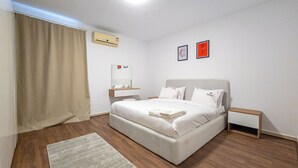 A neatly arranged bedroom with a bed, bedside tables, a nightstand, a rug, and a window with curtains. - Pharaohs Residence New Cairo El Rehab (New Cairo El rehab)