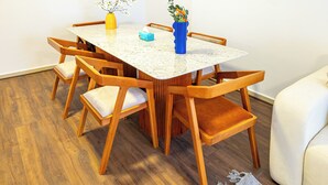 A dining area with a marble table, wooden chairs, and two vases with flowers. - Pharaohs Residence New Cairo El Rehab (New Cairo El rehab)