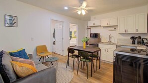 A compact living space with a dining area, kitchenette, and a door leading to another room. - 2BR Houston Haven, Playground, Prime Location (Houston)