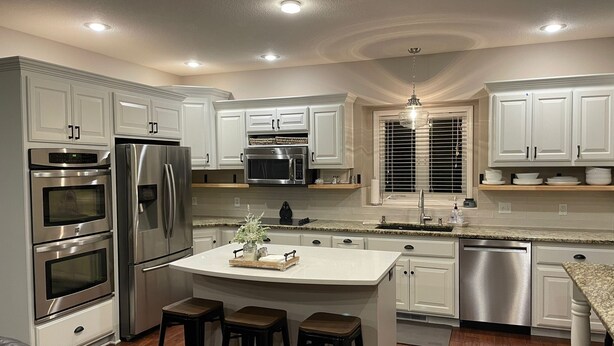 A modern kitchen with white cabinets, stainless steel appliances, a central island with stools, and a pendant light. - Beautiful 4 bedroom Country Estate in Liberty. Minutes from downtown KC. (Liberty)
