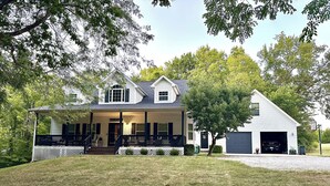 A two-story house with a porch, a garage, and a well-maintained lawn. - Beautiful 4 bedroom Country Estate in Liberty. Minutes from downtown KC. (Liberty)