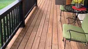 A wooden deck with a railing, a flag, outdoor furniture, and a potted plant. - Beautiful 4 bedroom Country Estate in Liberty. Minutes from downtown KC. (Liberty)
